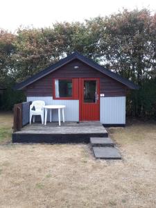 a smallshed with a table and a chair in front of it at Grindsted Aktiv Camping & Cottages in Grindsted