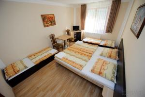 - une chambre avec 2 lits, une table et un bureau dans l'établissement Horský hotel Eva, à Svätý Jur