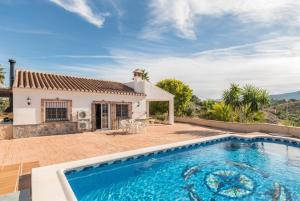 une villa avec une piscine en face d'une maison dans l'établissement Chalet andaluz Los Alberos, à Coín