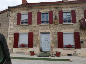 ein Gebäude mit roten Fensterläden und einem Hund auf der Fensterscheibe in der Unterkunft Le Bord d'eau in Montbard