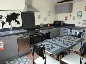 a kitchen with a stove and a table with chairs at Le Bord d'eau in Montbard