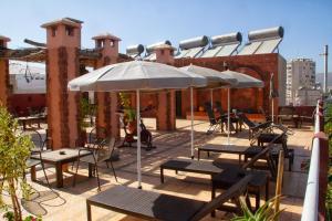 d'une terrasse avec des tables, des chaises et un parasol. dans l'établissement Apparts-hôtel ISNI, à Agadir