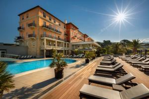 een resort met een zwembad en stoelen en een gebouw bij Imperial Valamar Collection Hotel in Rab