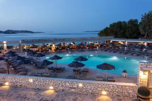 a large pool with tables and chairs and umbrellas at Saint Andrea Seaside Resort - Adults Only in Naousa