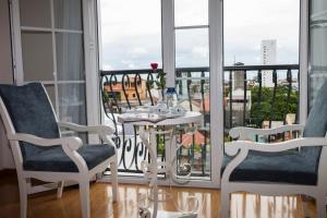 フエにあるホテル ラ ペルルのテーブルと椅子2脚、バルコニーが備わる客室です。