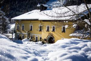żółty dom w śniegu z terenami pokrytymi śniegiem w obiekcie Ferienhotel Gasthof zur Post w mieście Untertauern