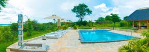 a swimming pool with chairs and an umbrella at Fort Murchison Lodge by NATURE LODGES LTD in Pakwach East