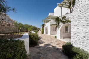 a white house with a stone walkway at Saint Andrea Seaside Resort - Adults Only in Naousa