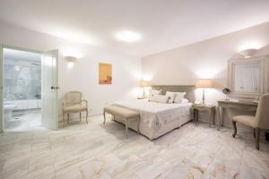 a white bedroom with a bed and a bathroom at Saint Andrea Seaside Resort - Adults Only in Naousa