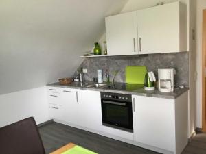 een keuken met witte kasten en een groen apparaat bij Ferienwohnung Rossis Nüst, 31516 in Uplengen