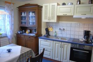 - une cuisine avec des placards blancs, un évier et une table dans l'établissement Ferienhaus Hermann, 35522, à Uplengen