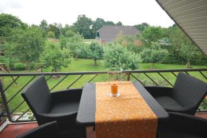 a table and chairs on a balcony with a view of a park at Ferienwohnung Rossis Nüst, 31516 in Uplengen