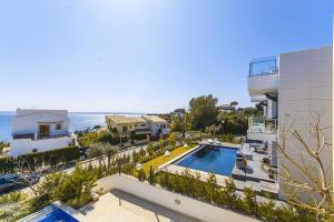 a building with a swimming pool next to the ocean at YupiHome Villa Aqua in Alcudia