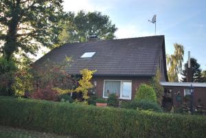 een huis met een zwart dak en een heg bij Ferienwohnung Am Moor, 35629 in Uplengen