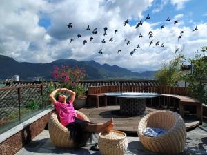 a woman sitting in a chair with a flock of birds at Floral Tengchong Mountain Residence in Tengchong