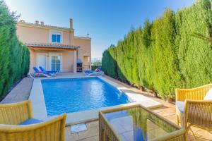 a swimming pool with chairs and a house at YupiHome Villa Roser in Alcudia