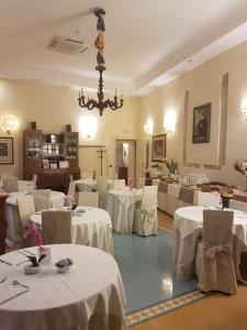 un restaurante con mesas y sillas blancas y una lámpara de araña en Domus Mariae Albergo, en Siracusa