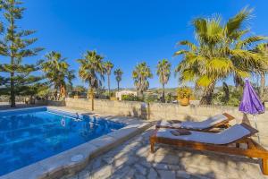 uma piscina com duas espreguiçadeiras e um guarda-sol em YupiHome Caseta de Vernissa em Santa Margalida
