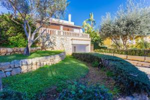 a house with a stone wall and a yard at YupiHome Villa Ca S'Anglès in Alcudia