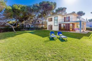 une cour avec deux chaises et une maison dans l'établissement Villa de les Aguiles, à Alcúdia
