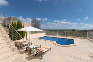 a swimming pool with a table and an umbrella at YupiHome Villa Es Sequer in Maria de la Salut