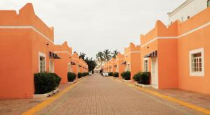 an empty street with orange buildings and palm trees at Star Emirates Garden Villas in Salalah