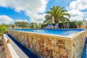 een zwembad met een stenen muur en 2 stoelen bij YupiHome Finca Can Tomeu in Montuiri