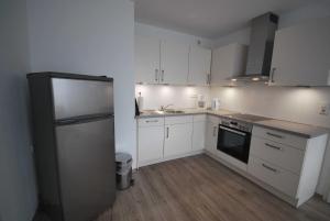 a kitchen with white cabinets and a stainless steel refrigerator at Ferienwohnung Anne, 35657 in Uplengen