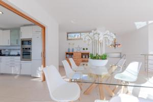 a dining room with a glass table and white chairs at YupiHome Villa Alcanada Lighthouse in Alcanada