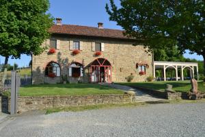 a large brick building with red flowers on it at Relais Borgo del Gallo in Acqui Terme