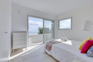 Dormitorio blanco con cama y ventana grande en YupiHome Son Serra First Line Villa, en Son Serra de Marina