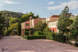 a house with a driveway in front of a mountain at Theo Pool Villa Magnificent Sea View in Kapandrítion