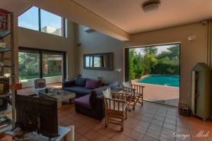 sala de estar con sofá, mesa y piscina en Theo Pool Villa Magnificent Sea View, en Kapandrítion