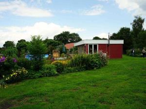 a small red shed in a field of grass at Ferienwohnung Am Traumgarten, 35646 in Uplengen