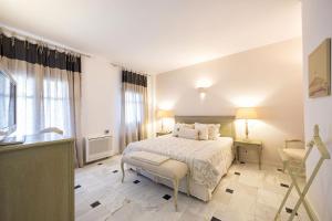 a white bedroom with a bed and a window at Saint Andrea Seaside Resort - Adults Only in Naousa