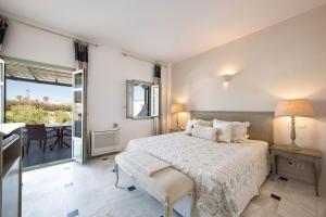 a white bedroom with a bed and a balcony at Saint Andrea Seaside Resort - Adults Only in Naousa