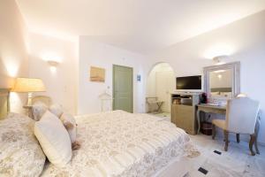 a bedroom with a bed and a desk and a television at Saint Andrea Seaside Resort - Adults Only in Naousa