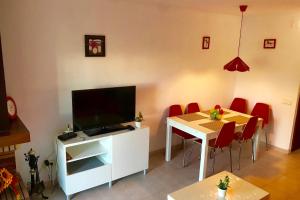 a living room with a tv and a table with chairs at MEDDAYS CHALET EL SOL in Miami Platja