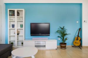 a living room with a tv on a blue wall at Yagen boutique apartments in Haifa