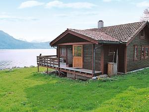 a wooden house on the shore of a lake at Three-Bedroom Holiday home in Nordfjordeid 2 in Heggjafrislia