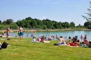 a group of people laying on the grass near a lake at Ferienwohnung Frieda, 65207 in Moormerland