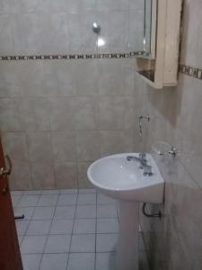 een badkamer met een witte wastafel en een spiegel bij Hospedaje BellaVilla in Bell Ville +29 foto's