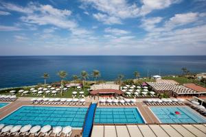 
a beach area with a pool, chairs, and tables at Merit Park Hotel Casino & SPA in Kyrenia
