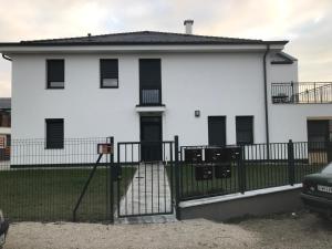 ein weißes Haus mit einem schwarzen Zaun in der Unterkunft Jada Lakás in Keszthely