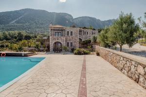 a house with a swimming pool and a stone wall at Salakos Villas in Sálakos