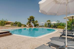 a swimming pool with chairs and an umbrella at Salakos Villas in Sálakos