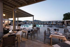 a restaurant with tables and chairs and a pool at Saint Andrea Seaside Resort - Adults Only in Naousa