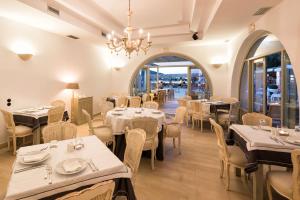 a restaurant with tables and chairs and a chandelier at Saint Andrea Seaside Resort - Adults Only in Naousa