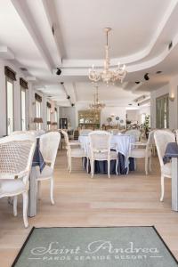 a dining room with white tables and chairs and a chandelier at Saint Andrea Seaside Resort - Adults Only in Naousa