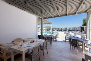 a restaurant with tables and chairs and a pool at Saint Andrea Seaside Resort - Adults Only in Naousa
